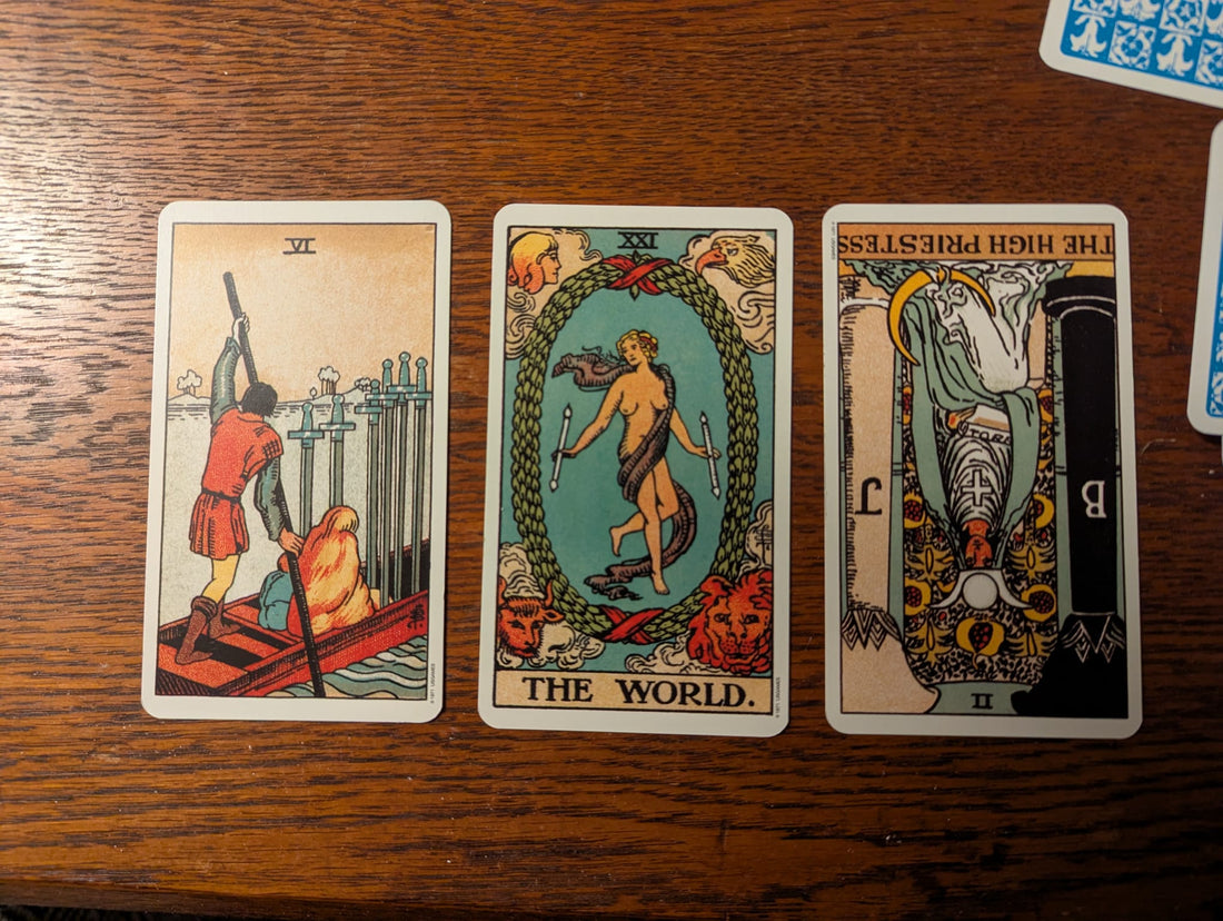 Tarot reading image revealing profound guidance for moving on from loss with the Six of Swords, The World, and reversed High Priestess cards