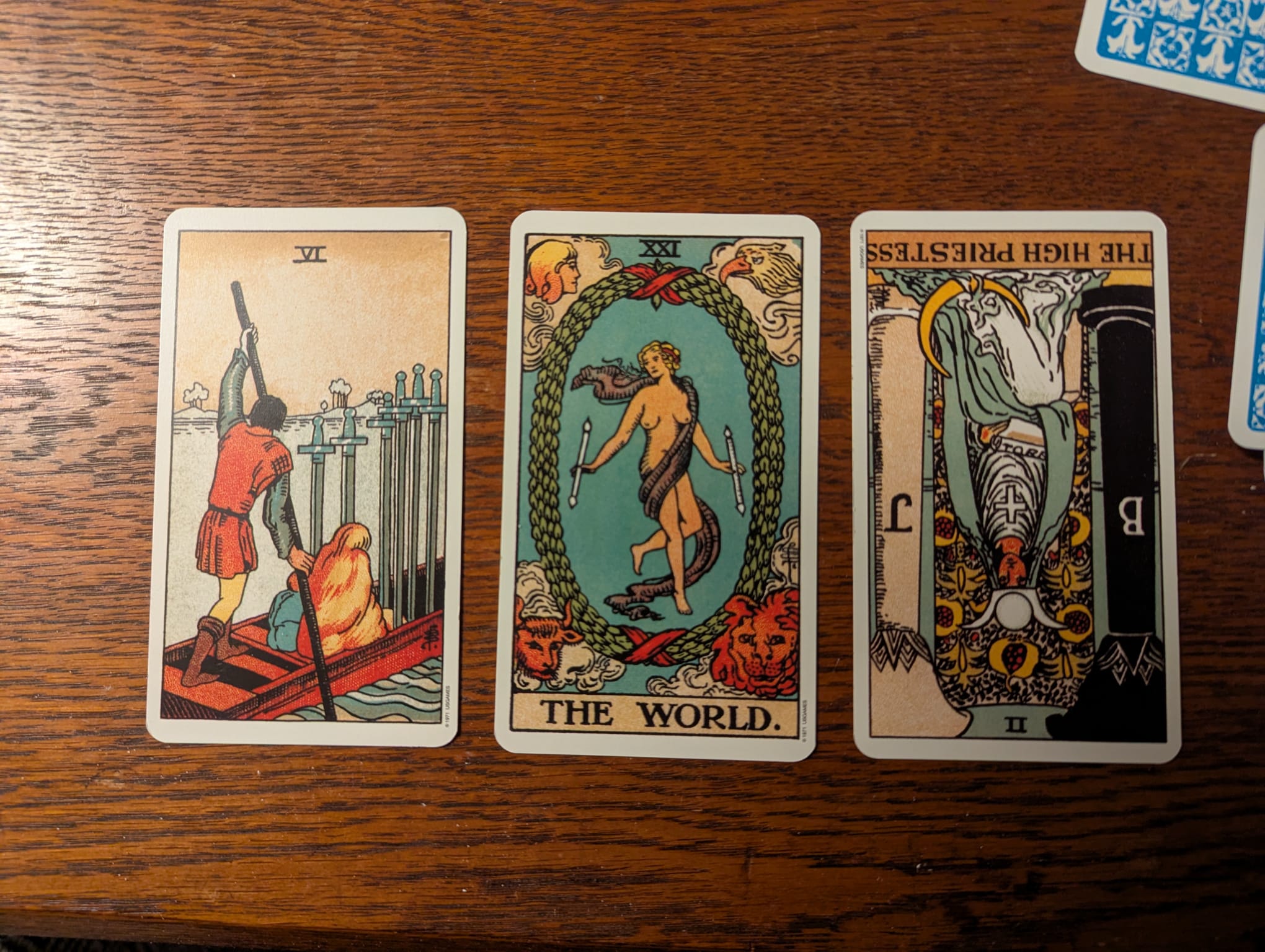Tarot reading image revealing profound guidance for moving on from loss with the Six of Swords, The World, and reversed High Priestess cards